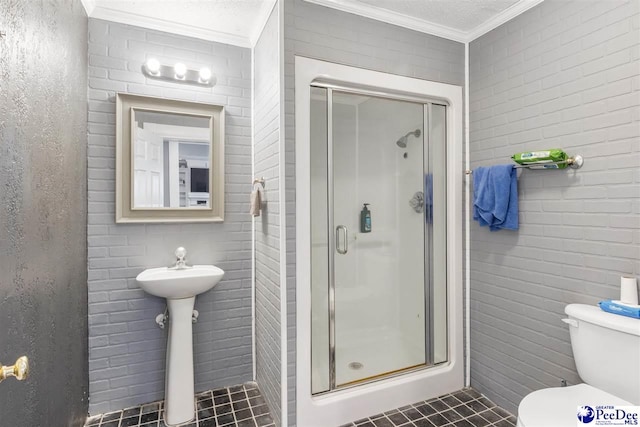 bathroom featuring tile patterned floors, toilet, brick wall, a shower stall, and crown molding