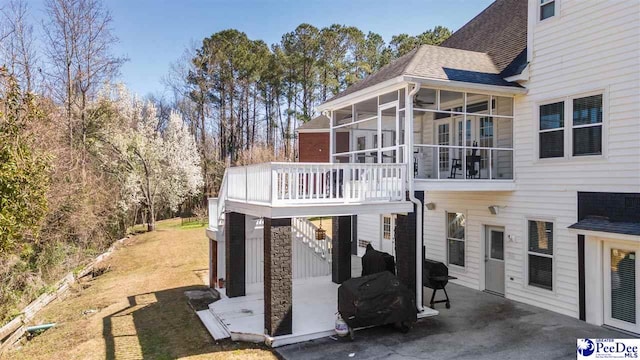 view of property exterior featuring stairway, roof with shingles, a lawn, a sunroom, and a patio