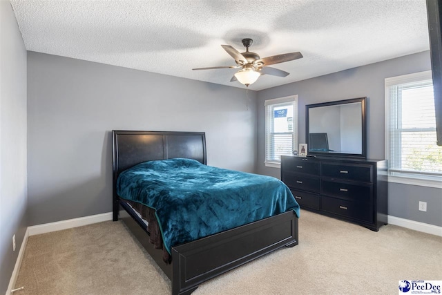 bedroom with baseboards, light carpet, a textured ceiling, and a ceiling fan