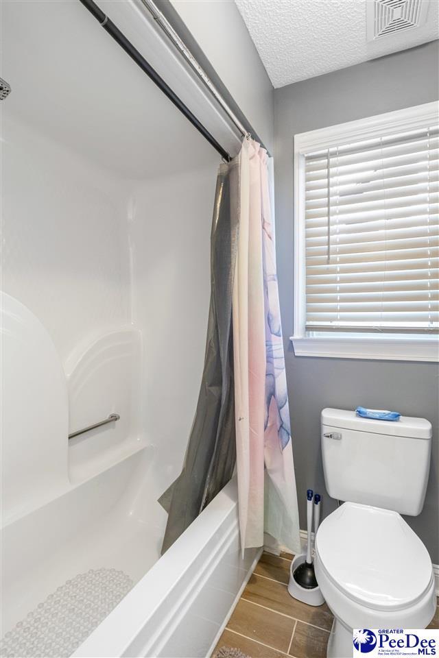 full bathroom with visible vents, a textured ceiling, toilet, and wood finish floors