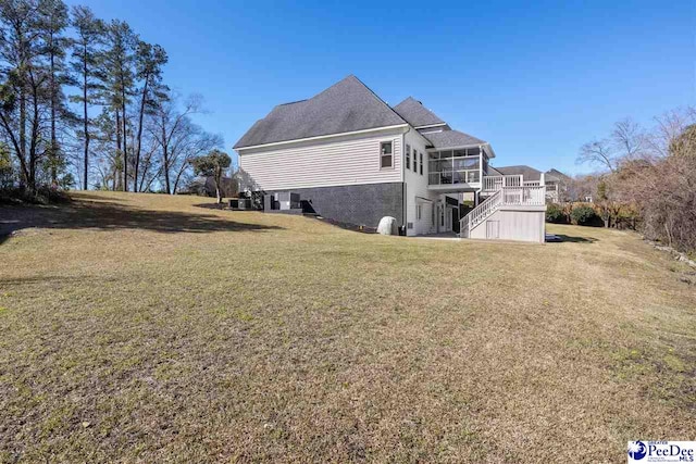 view of side of home featuring stairs, central AC, a lawn, a deck, and a sunroom