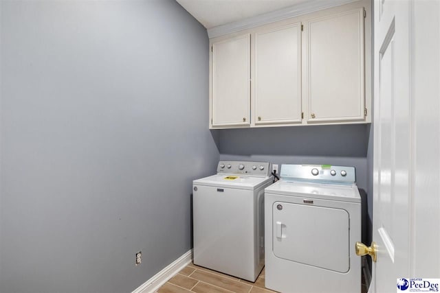 laundry area with washer and dryer, baseboards, cabinet space, and wood finish floors