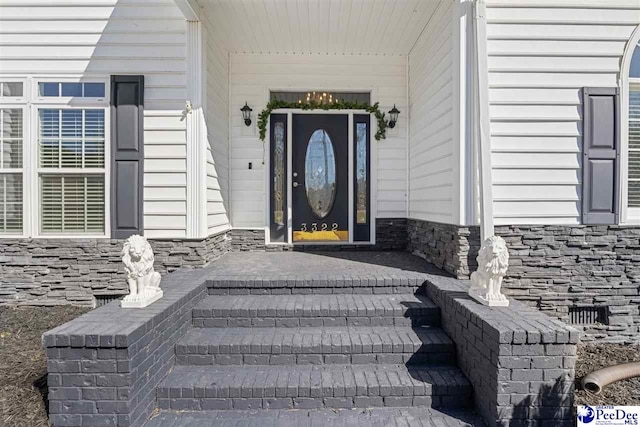 property entrance with stone siding and a porch