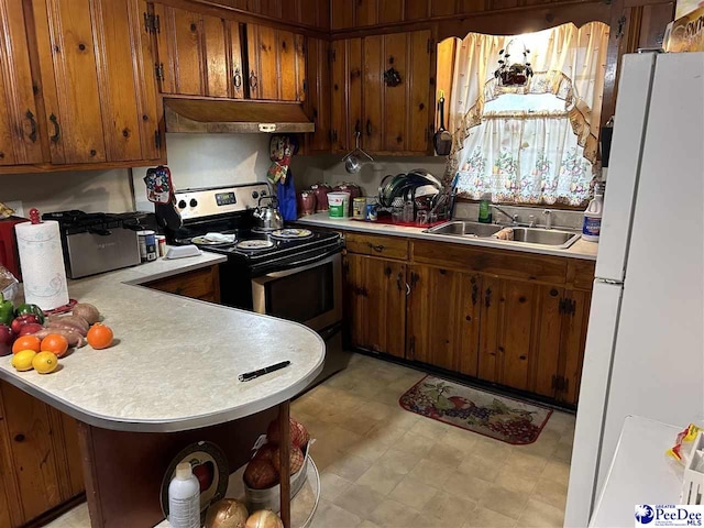 kitchen with under cabinet range hood, light countertops, freestanding refrigerator, and stainless steel range with electric cooktop