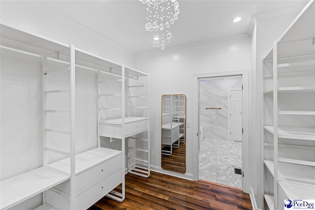 walk in closet featuring dark wood-type flooring and a notable chandelier