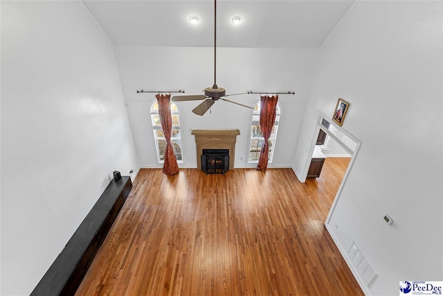 unfurnished living room with light wood-style floors, a fireplace, baseboards, and a ceiling fan