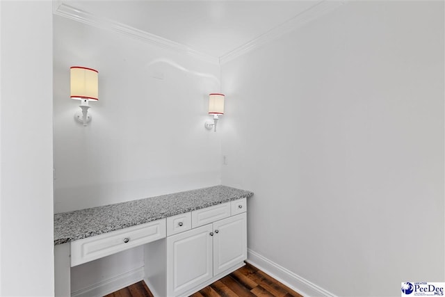 room details featuring crown molding, built in desk, baseboards, and wood finished floors