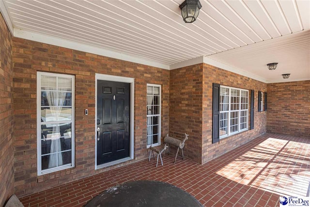 property entrance with a patio and brick siding