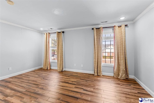 spare room with ornamental molding, visible vents, and hardwood / wood-style floors