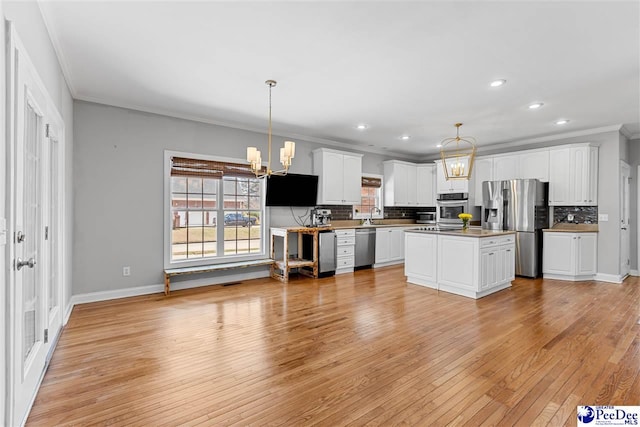 kitchen featuring an inviting chandelier, white cabinetry, stainless steel appliances, and decorative light fixtures