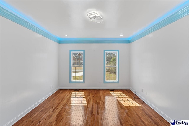 spare room with ornamental molding, hardwood / wood-style floors, and baseboards