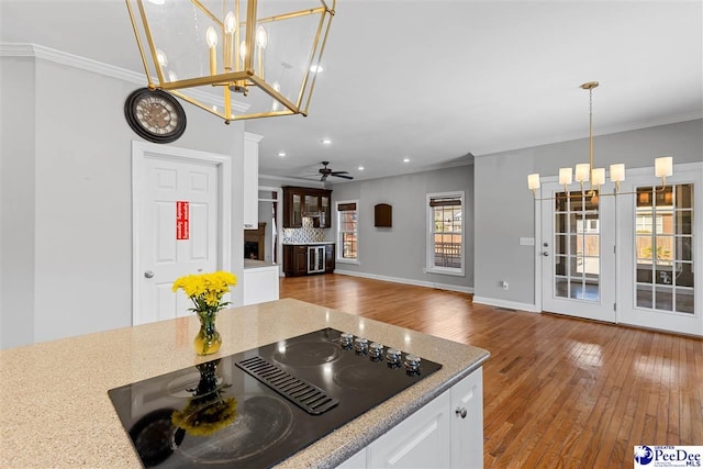 kitchen with white cabinets, black electric stovetop, open floor plan, and crown molding