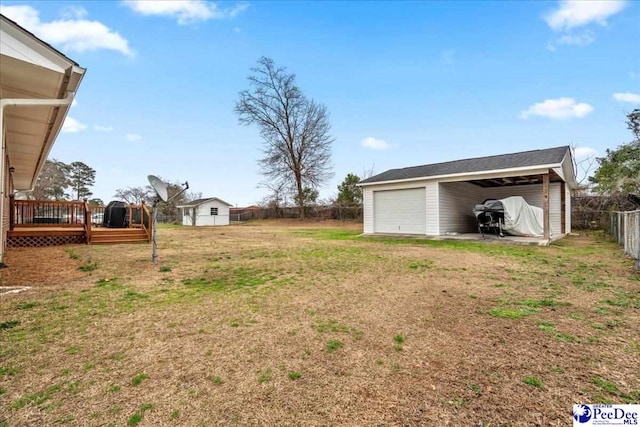 view of yard featuring a garage, a wooden deck, and an outdoor structure