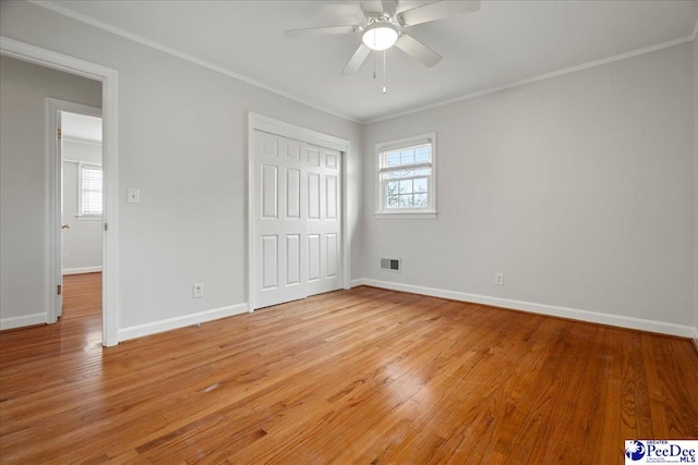 unfurnished bedroom featuring ceiling fan, ornamental molding, light hardwood / wood-style floors, and a closet