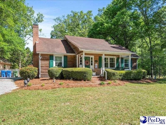 ranch-style home featuring a porch, a front yard, and a chimney