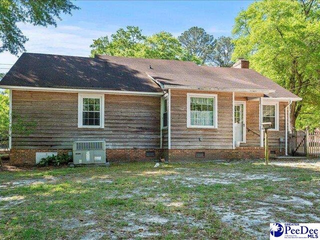 back of house featuring cooling unit, a lawn, crawl space, and a chimney