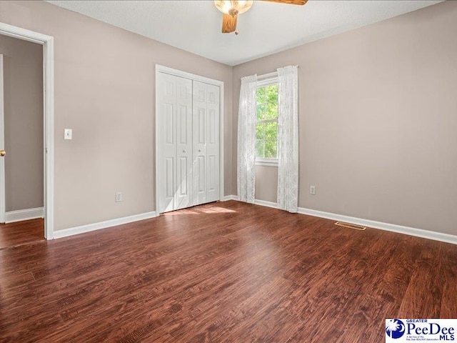 unfurnished bedroom featuring baseboards, visible vents, wood finished floors, and a closet