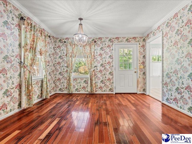 unfurnished dining area featuring baseboards, wallpapered walls, hardwood / wood-style flooring, and a notable chandelier