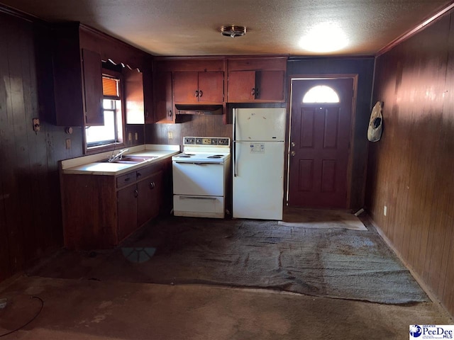 kitchen with wooden walls, white appliances, a sink, and under cabinet range hood