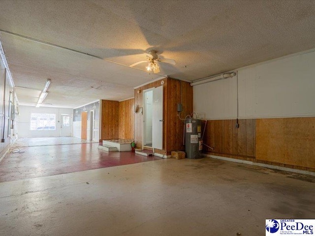 garage with ceiling fan, electric water heater, and wood walls