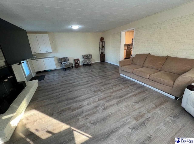 living room with brick wall and hardwood / wood-style floors