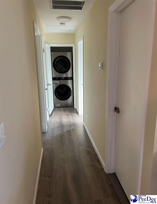 corridor with stacked washing maching and dryer and dark hardwood / wood-style floors