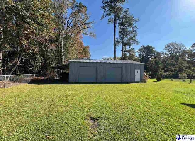 view of yard with a garage, a carport, and an outbuilding