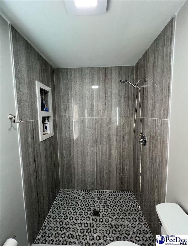 bathroom with a tile shower and toilet