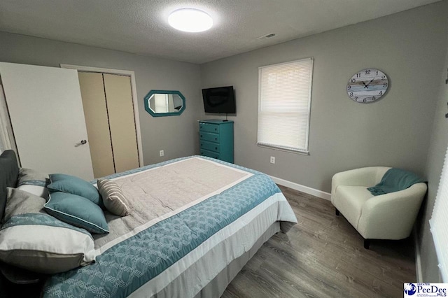 bedroom with dark hardwood / wood-style flooring and a textured ceiling