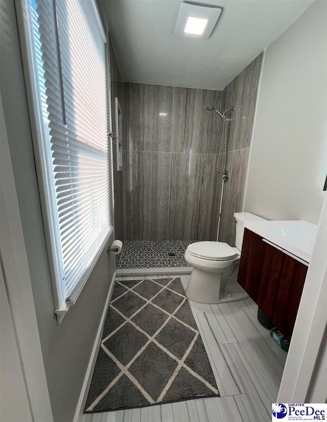 bathroom with vanity, toilet, and a tile shower