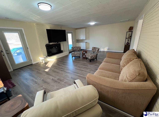 living room featuring brick wall, a fireplace, and hardwood / wood-style floors