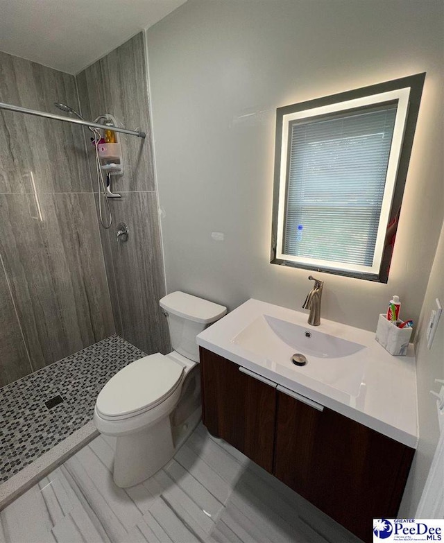 bathroom featuring tiled shower, vanity, and toilet