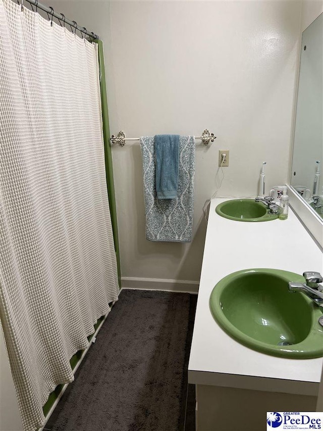 bathroom with a sink, baseboards, and double vanity