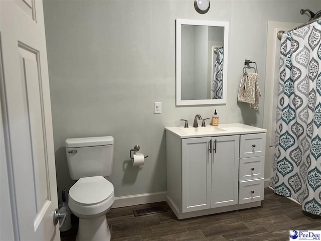 bathroom featuring wood finish floors, baseboards, vanity, and toilet