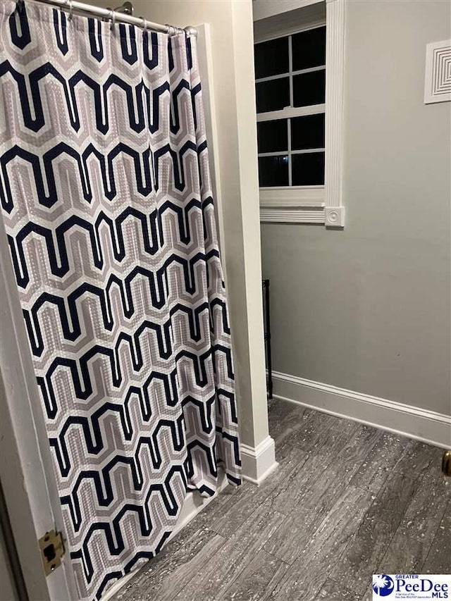 bathroom featuring a shower with curtain, visible vents, baseboards, and wood finished floors