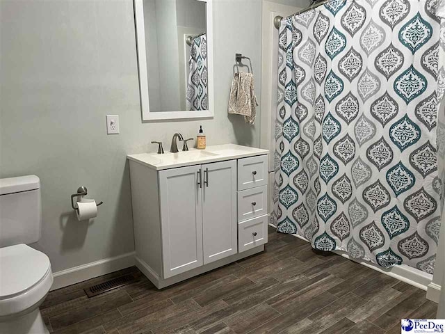 bathroom featuring toilet, vanity, wood finished floors, a shower with curtain, and baseboards