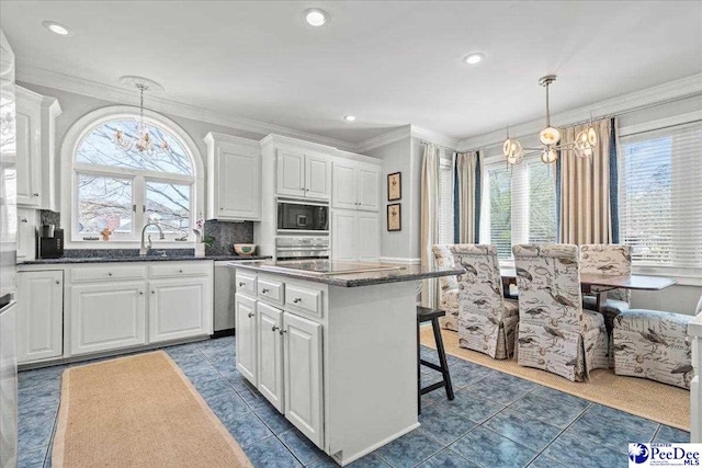 kitchen featuring a kitchen breakfast bar, a kitchen island, white cabinetry, appliances with stainless steel finishes, and crown molding