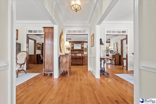 foyer entrance featuring a notable chandelier, crown molding, and light wood-style floors