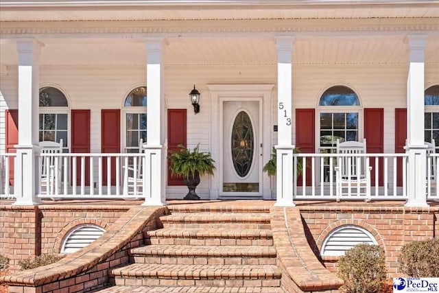 doorway to property with brick siding and covered porch