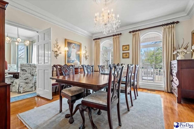 dining area featuring crown molding, light wood-style floors, and an inviting chandelier