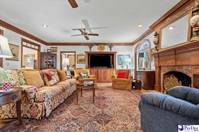 living area featuring a large fireplace, a ceiling fan, and ornamental molding