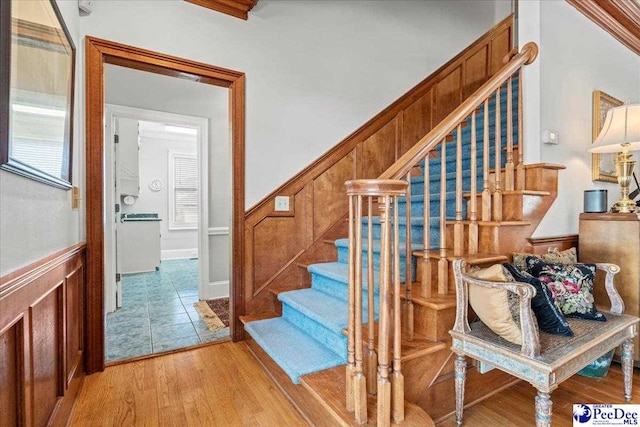 staircase with a wainscoted wall and wood finished floors