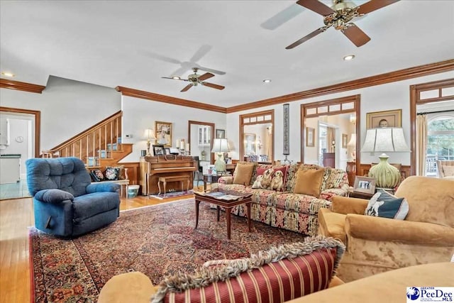 living area featuring wood finished floors, recessed lighting, crown molding, ceiling fan, and stairs