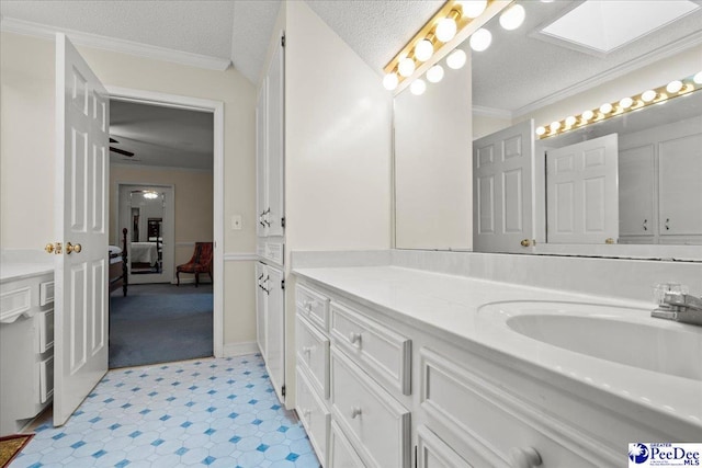 ensuite bathroom with crown molding, vanity, a skylight, ensuite bath, and a textured ceiling