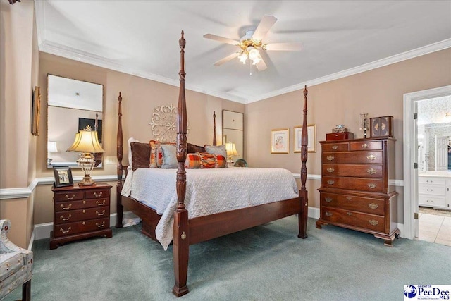 carpeted bedroom featuring baseboards, ensuite bathroom, ceiling fan, and ornamental molding