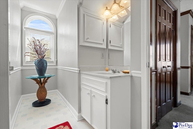 bathroom with vanity, crown molding, and baseboards