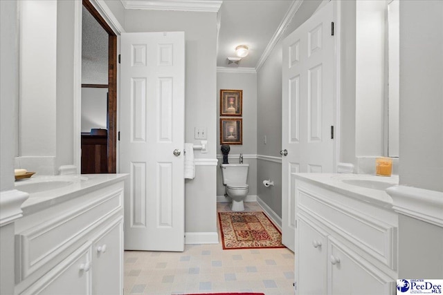 bathroom featuring a sink, ornamental molding, toilet, and two vanities