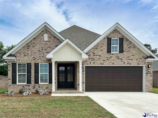 view of front of home featuring brick siding, driveway, french doors, a front yard, and a shingled roof