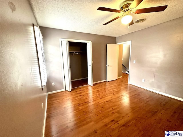 unfurnished bedroom with ceiling fan, a textured ceiling, light hardwood / wood-style floors, and a closet