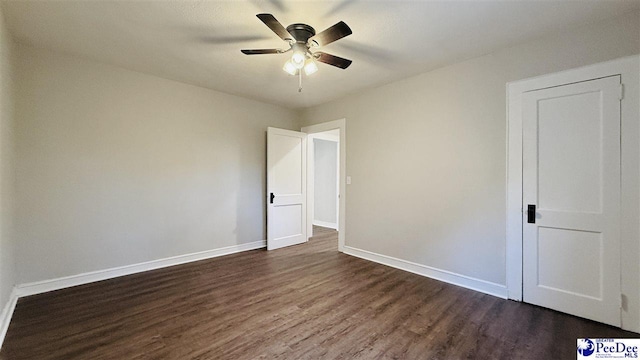 empty room with ceiling fan and dark hardwood / wood-style flooring